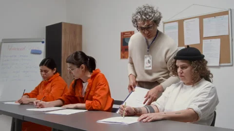 Inmates in Class Doing Tasks with Female Teacher Assisting during Lesson Stock Footage 328998071