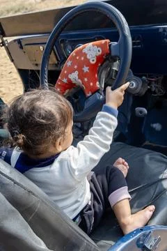 Innocent toddler cute expression while playing with motor van handle at day.. 写真素材
