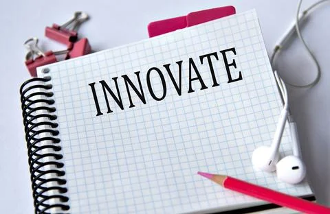 INNOVATE - word in a white notebook on a white background with headphones a.. Stock Photos