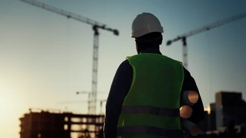 Innovation in construction, foreman walking on building site in sunset, rearview Stock Footage 318709610