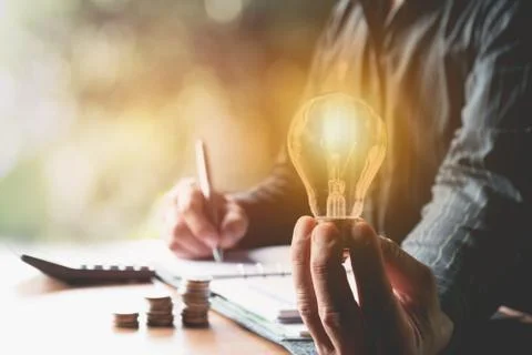 Innovation or creative concept of hand hold a light bulb with calculator. Stock Photos