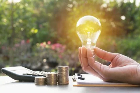 Innovation or creative concept of hand hold a light bulb with calculator. Stock Photos