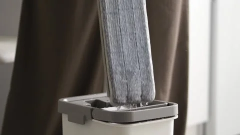 The innovative cleaning tool is a mop handle placed in a grey bucket, which high Stock Footage 312574393