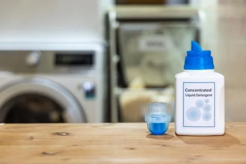 Innovative compact concentrated laundry liquid detergent against washing mach Stock Photos