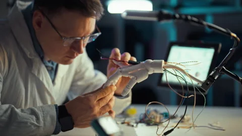 Innovative engineer building a robotic hand in a modern lab setting Stock Footage 331297338