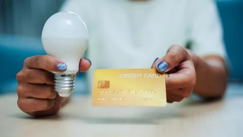 Innovative technology integration using a credit card to power a light bulb.. 스톡 사진