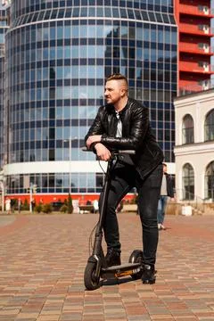 Innovative transport. Glad optimistic guy leaning on electric scooter Stock Photos