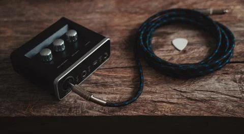 Inputting a P10 cable on the audio interface with a guitar pick in the scene. Stock Photos