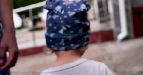 Inquisitive Toddler: Blue-Capped Boy Gazing into the Lens and Walking Away Stock Footage 243197786