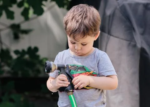 Inquisitive toddler is exploring objects in the backyard Stock Photos