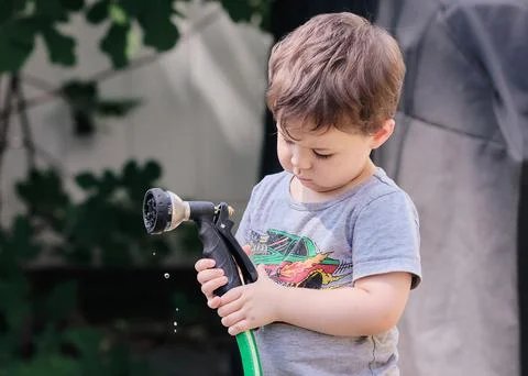Inquisitive toddler is exploring objects in the backyard Stock Photos