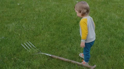 An Inquisitive Toddler Playing and Exploring the Garden with a Tool Stock Footage 313565225