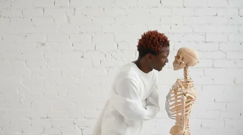 An insane black man wearing a straitjacket dance and looking at human skeleton Video stock 59090332