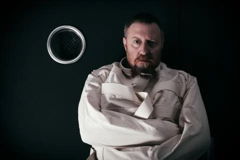 Insane man in a cell wearing a straitjacket Stock Photos