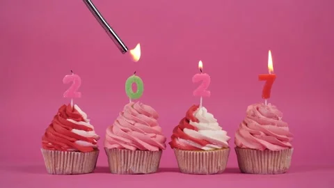 The inscription 2027 made of burning multi-colored candles on delicious cupcakes Stock Footage 274665014