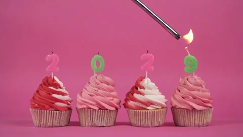 The inscription 2029 made of burning multi-colored candles on delicious cupcakes Stock Footage 275331691