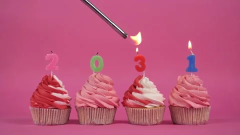 The inscription 2031 made of burning multi-colored candles on delicious cupcakes Stock Footage 275331967