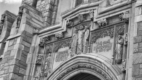 Inscription above a church entrance with statues of saints Stock Photos