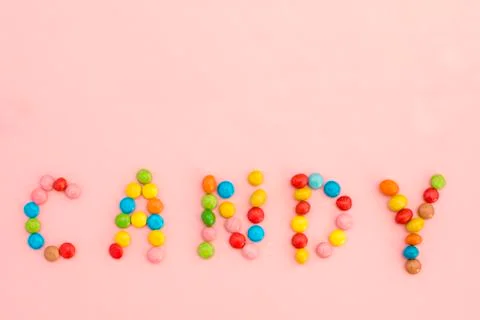 The inscription Candy of colorful candies on a pink background Stock Photos