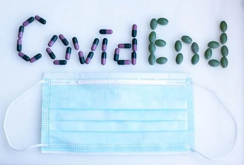 Inscription Covid End from colored tablets with medical mask Stock Photos