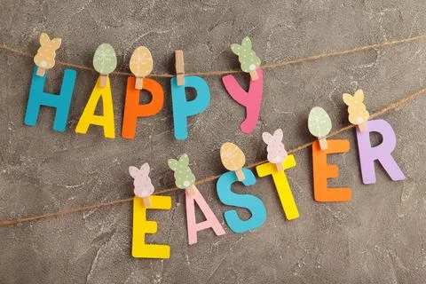 Inscription Happy Easter on grey background, a rope with clothespins. The con Stock Photos