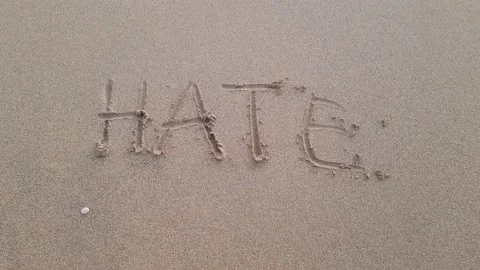Inscription Hate on a sandy beach washed away by the waves of the sea Stock Footage 220509522