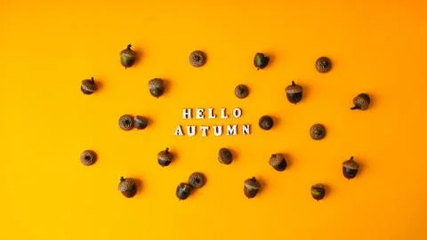 Inscription HELLO AUTUMN text Pattern with acorns on the yellow background. A Stock Photos