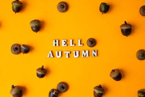 Inscription HELLO AUTUMN text Pattern with acorns on the yellow background. A Stock Photos
