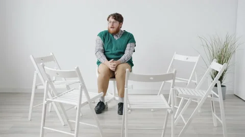 Insecure guy sitting in white room alone... | Stock Video | Pond5