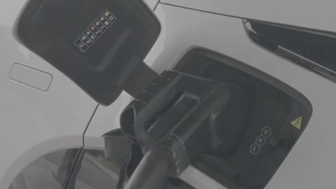 Insert the charging gun into the electric vehicle's charging port. Stock Footage 344011124