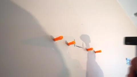 Insert cleat in the perforated gray wall and hit with a hammer Stock Footage 141082766