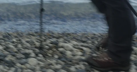 Insert of hiking boots on pebble beach Stock Footage 90078942