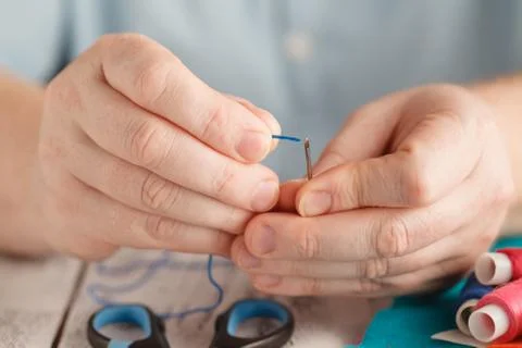 Insert the thread in needle by man hand Stock Photos