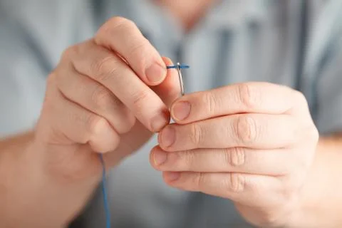 Insert the thread in needle by man hand Stock Photos