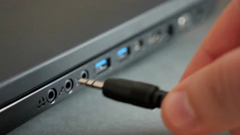 Inserting 3.5 mm audio cable into the side port of a laptop computer. Stock Footage 132382157