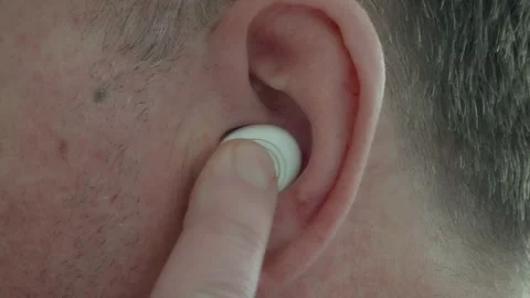 Inserting and turning on a white Bluetooth earphone into your ear. Close-up Stock Footage 304735547