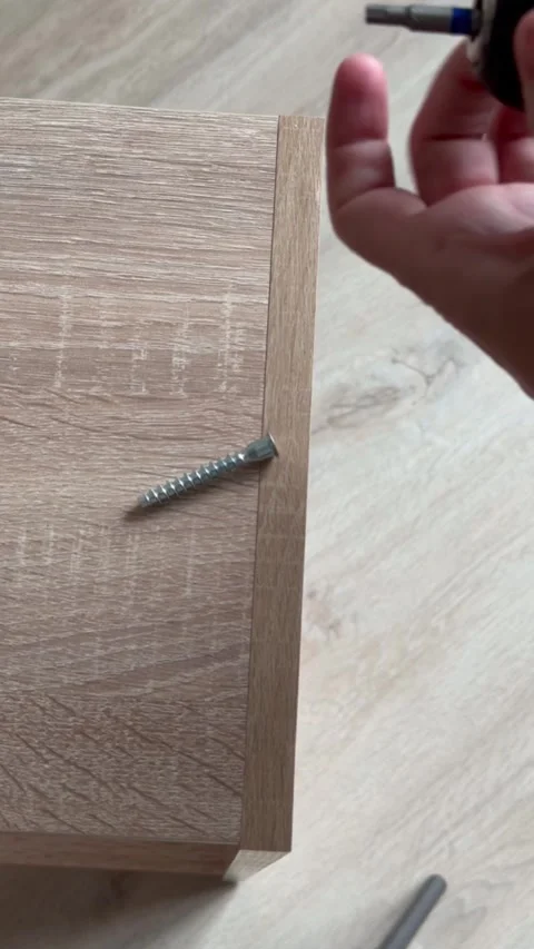 Inserting bit into electric screwdriver and screwing screw into furniture panel Stock Footage 316820555