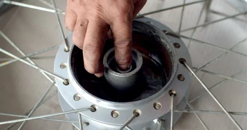 Inserting a central bushing into a motorcycle wheel hub, applying grease. Stock Footage 311665211