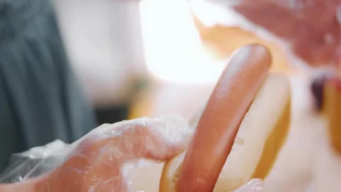 Inserting a cooked sausage into a split bread bun, 4K Stock Footage 341121887