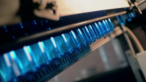 Inserting empty plastic bottle preforms into a conveyor belt 库存影片 149672687