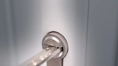 Inserting a key into the keyhole of a white plastic door close-up. Turning the Stock Footage 202138268
