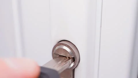 Inserting a key into a white door and turning it counterclockwise close-up Stock Footage 204996113