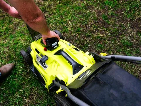 Inserting a lithium battery into cordless lawn mower Stock Photos