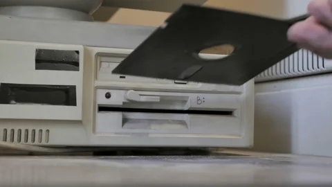 The inserting an old-style 5.25, 3.5 Inch floppy disks.  Old-style 1980s Stock Footage 157961391