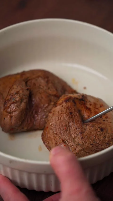 Inserting oven thermometer into lamb roast in ceramic dish Stock-Footage 334674189