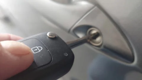 Inserting a physical car key into the door lock cylinder close-up Stock Footage 335072501