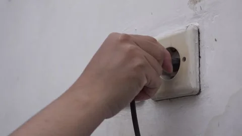 Inserting a plug into a wall socket by hand Stock Footage 283268800