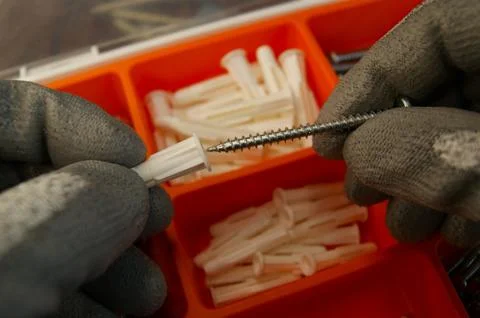 Inserting the screw into the plastic dowel. Builder's work process. Stock Photos