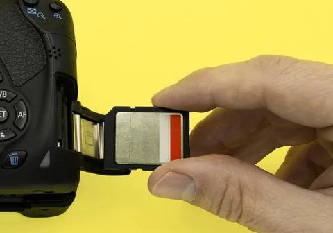 Inserting a sd type memory card into a dslr photo camera yellow background Stock Photos