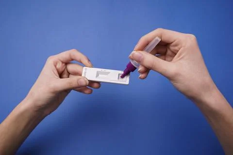 Inserting the solution into the COVID-19 coronavirus rapid self-test. Blue ba Stock Photos